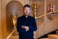 Michael Carrick appointed Man Utd interim manager standing before a trophy cabinet